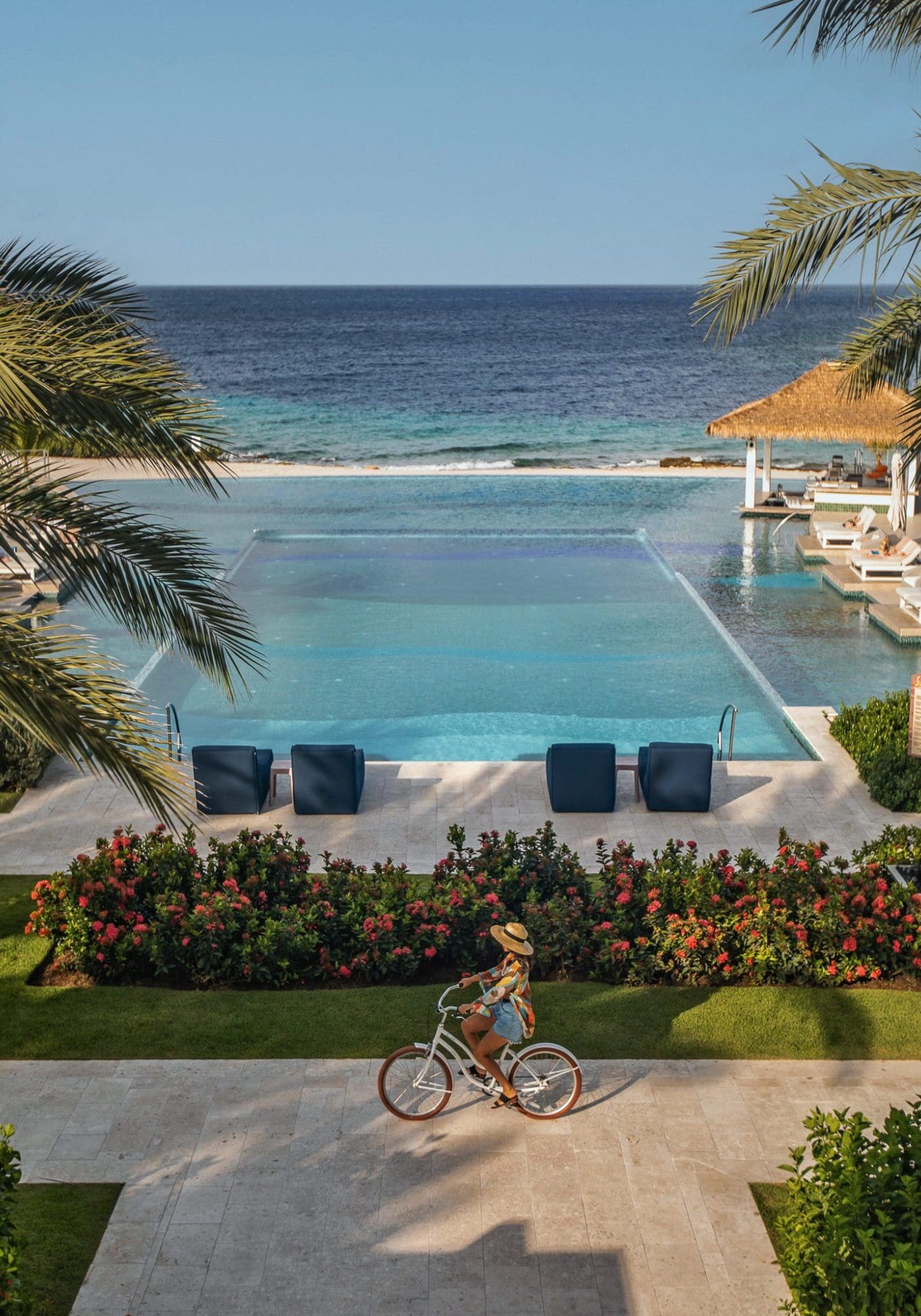 Anoushka cycles on a dutch bike past the double infinity pool at Sandals Royal Curacao