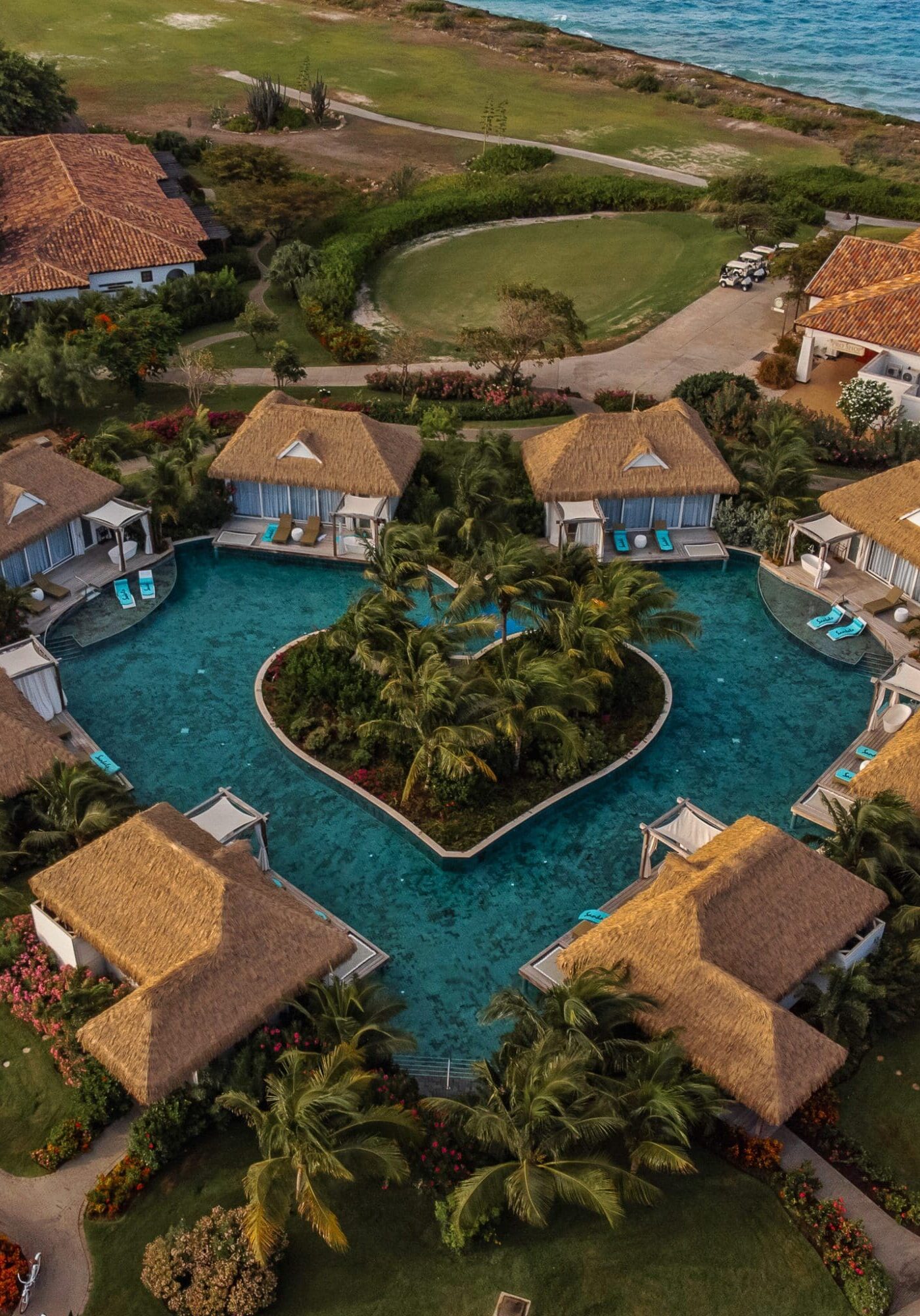 An aerial photograph of a heart shaped pool surrounded by the roofs of villas at Sandals Royal Curacao Resort